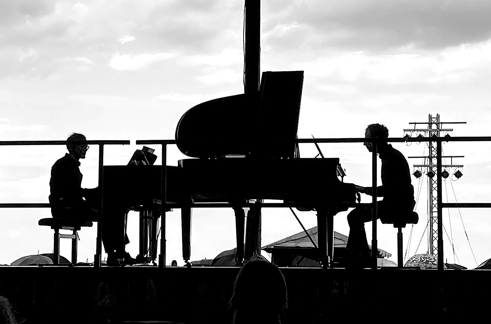 Zwei Pianisten sitzen sich an zwei Konzertflügeln gegenüber, im Gegenlicht